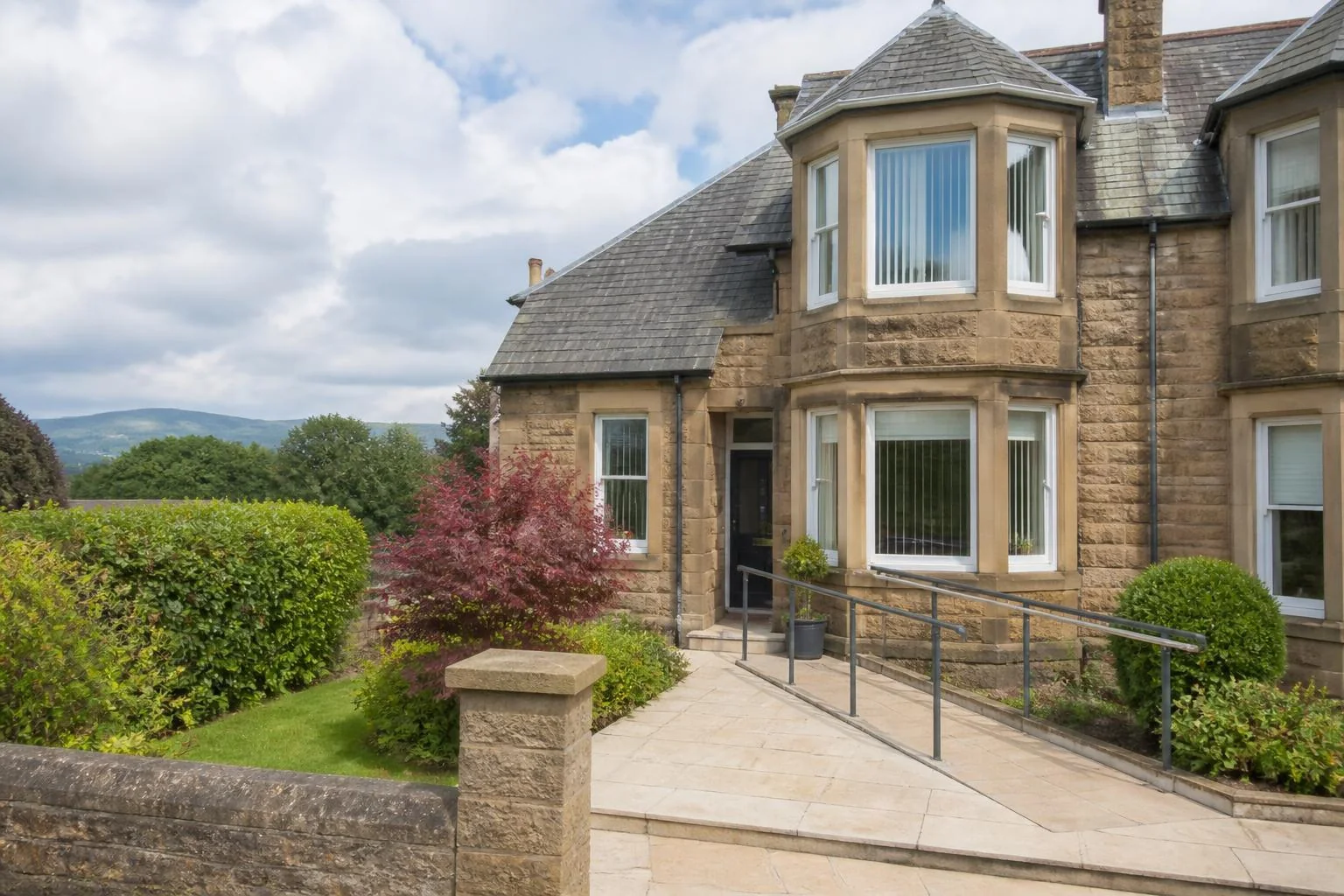 Representative traditional stone-built supported-living home in Central Scotland, with level access, a handrail and landscaped garden